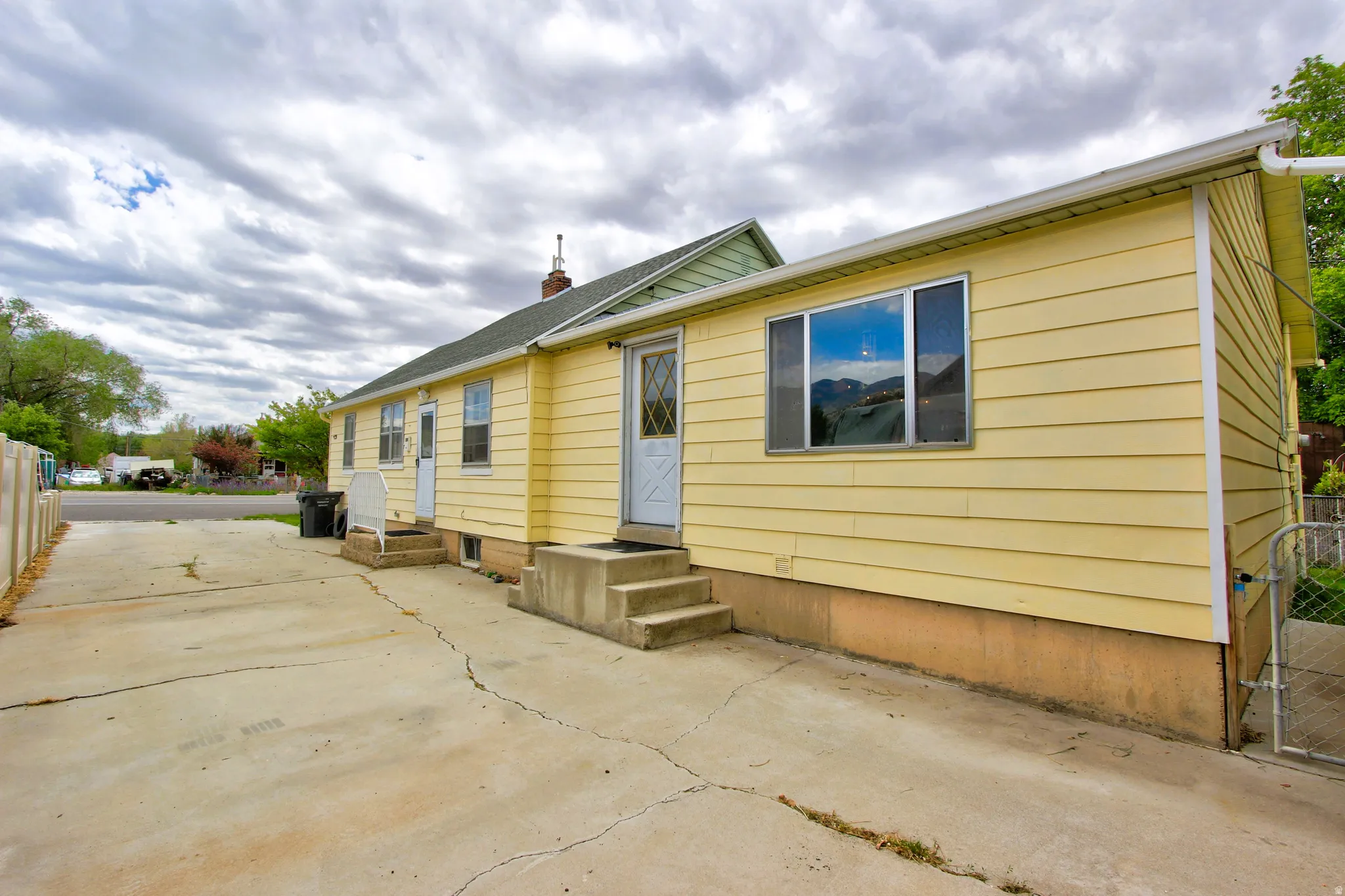 Yellow siding exterior with multiple entry doors and a concrete driveway