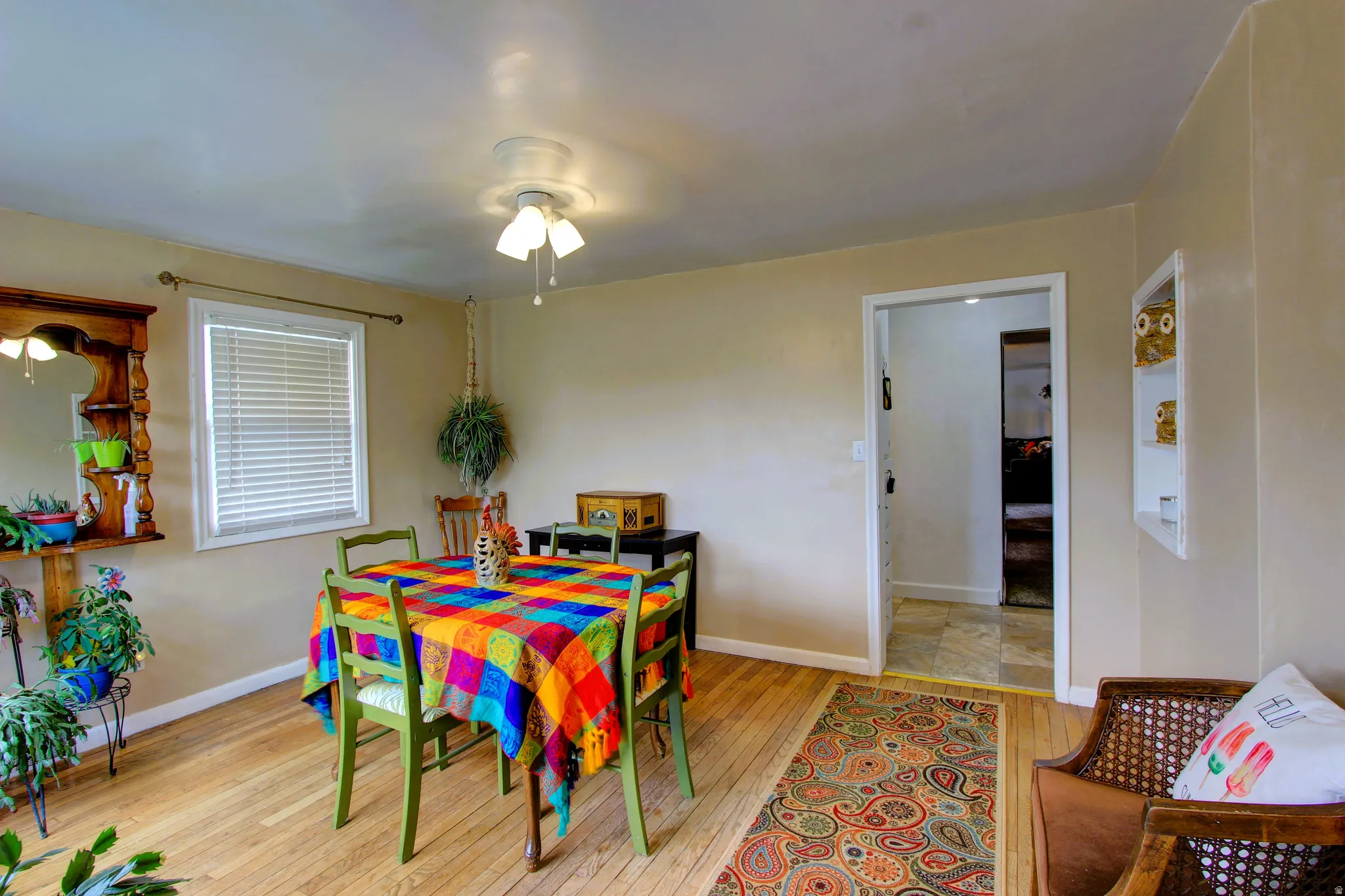 Bright room featuring wood-finish flooring, a white window with horizontal blinds, and a ceiling fan with light fixture