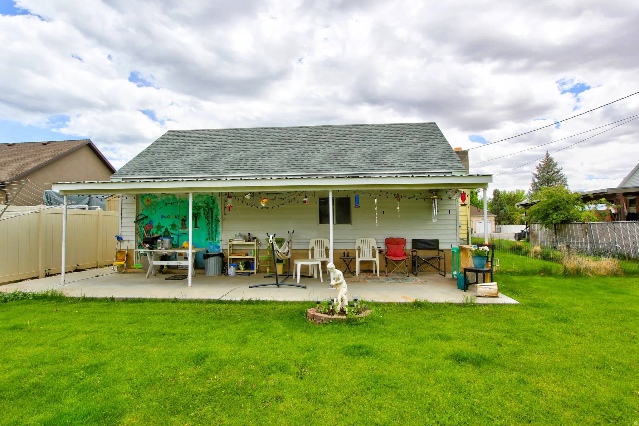 Expansive rear yard featuring a covered concrete patio, horizontal siding, and a gabled roofline