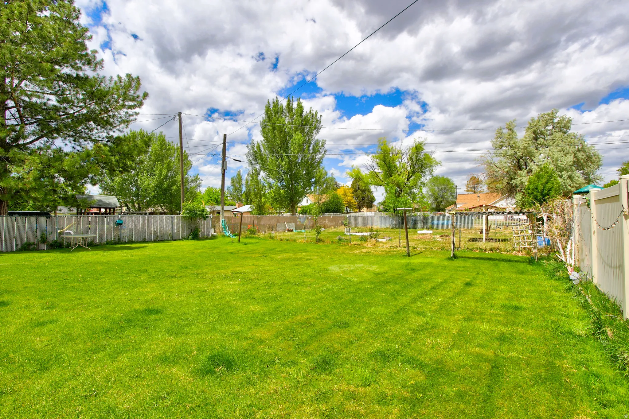 Expansive green lawn with established trees and surrounding perimeter fencing