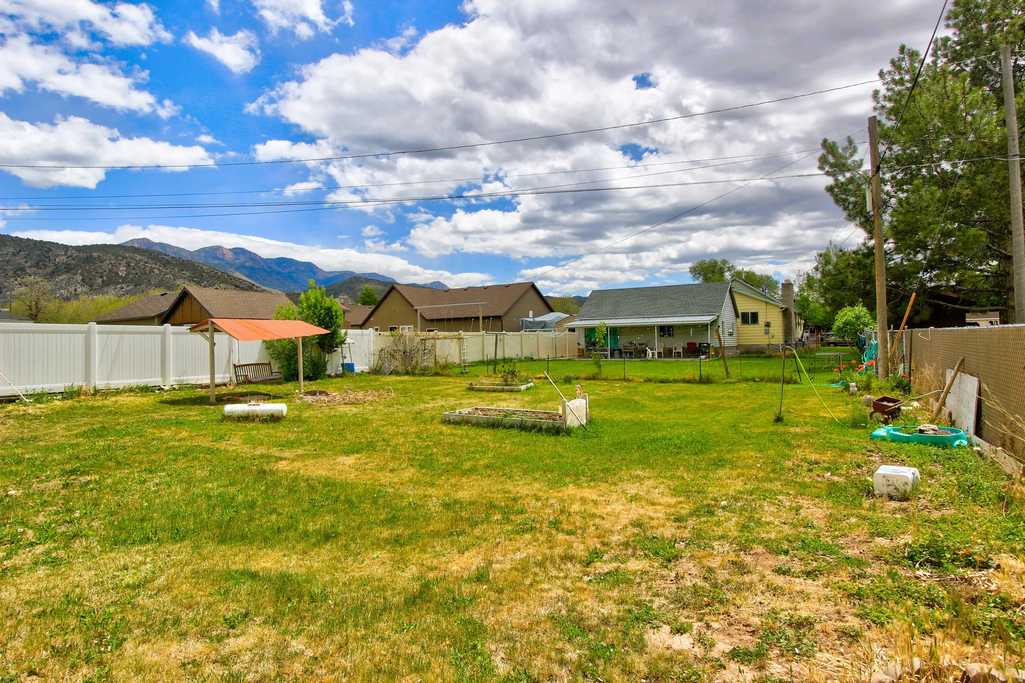 Expansive grassy yard area with a white vinyl fence