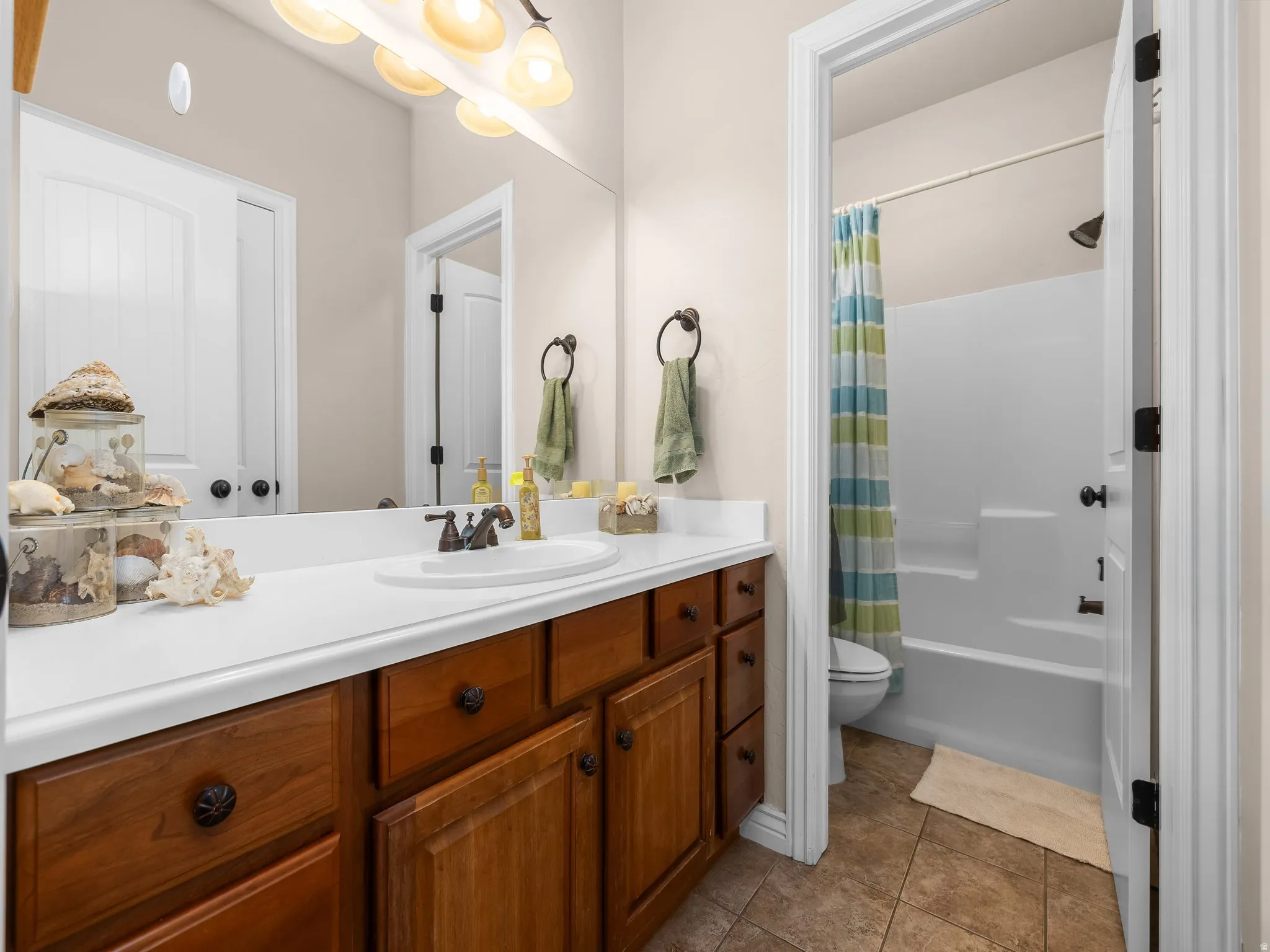 Bathroom vanity featuring a single basin sink, white countertop, and wood-finish cabinetry with dark hardware