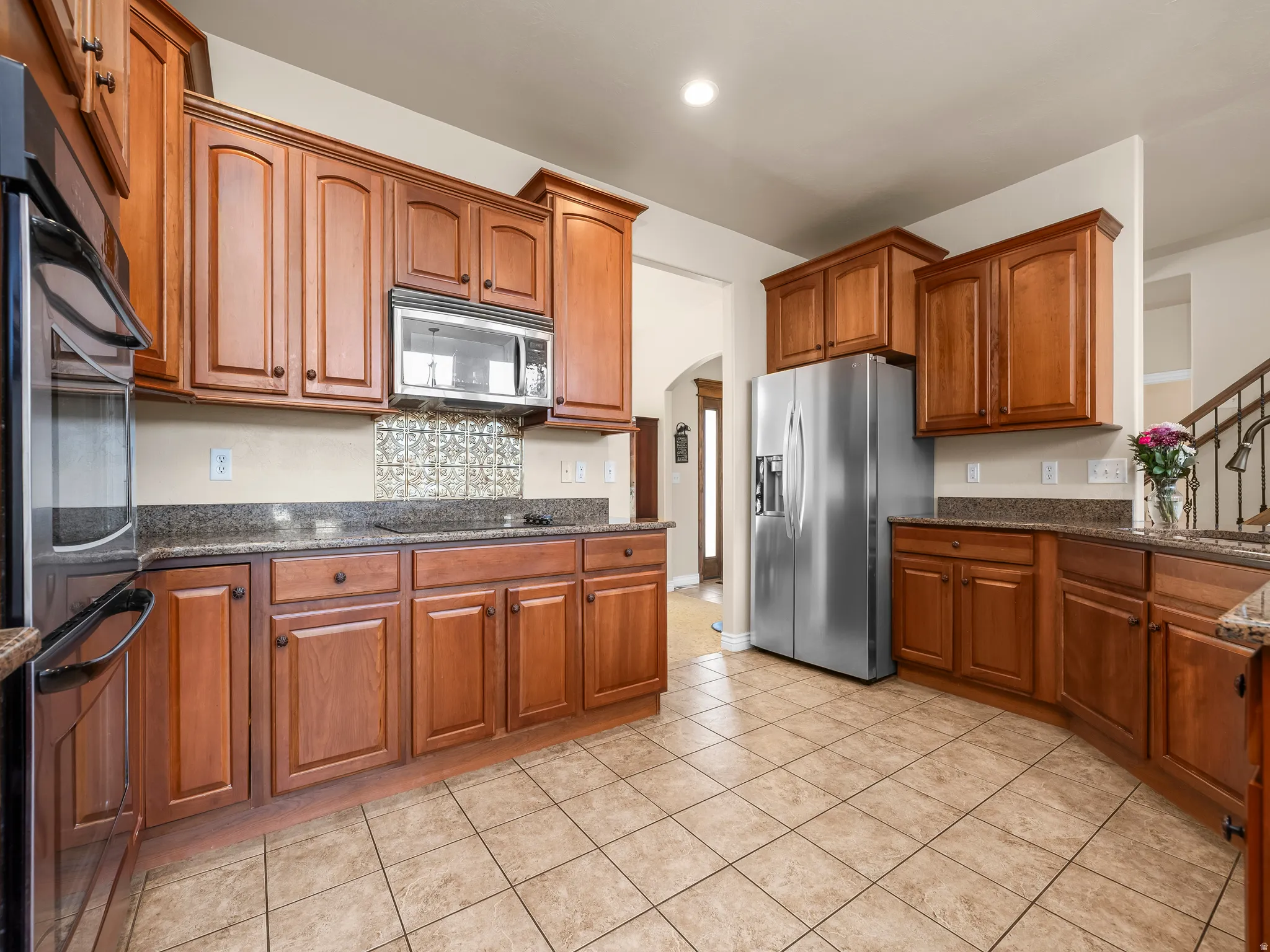 Kitchen featuring extensive wood cabinetry, granite countertops, stainless steel appliances, and a tile backsplash