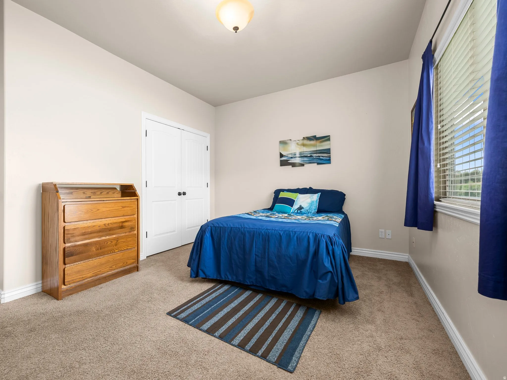 Bedroom featuring neutral wall paint, light brown carpeting, white baseboards, and a window with blinds