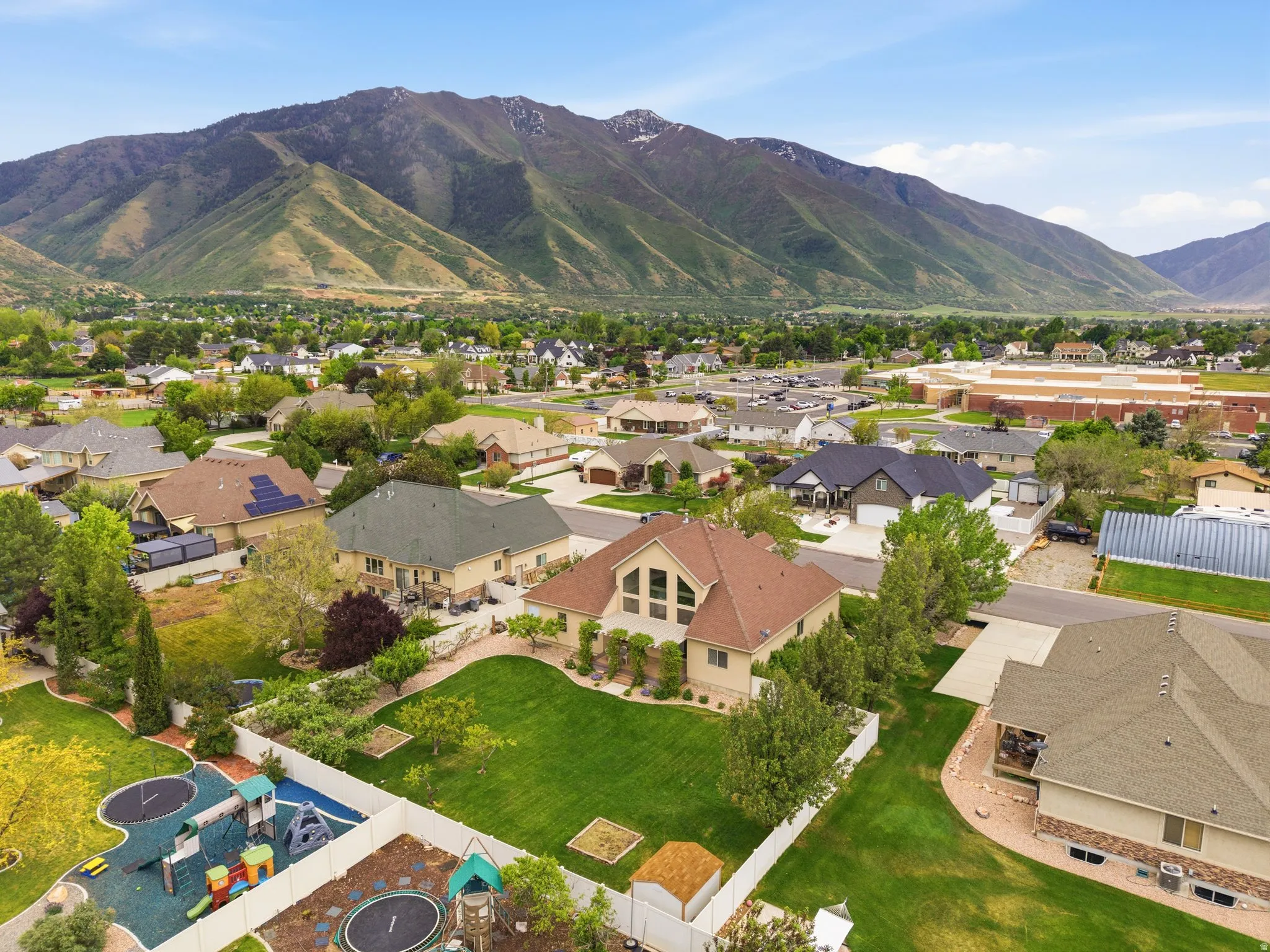 Expansive residential property featuring a large green lawn, mature landscaping, and a white privacy fence