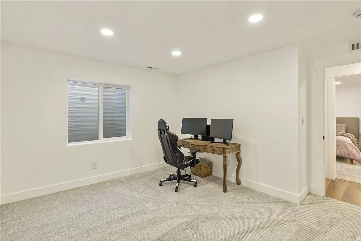 Spacious room with light gray carpeting, recessed ceiling lighting, a white framed window, and white baseboards