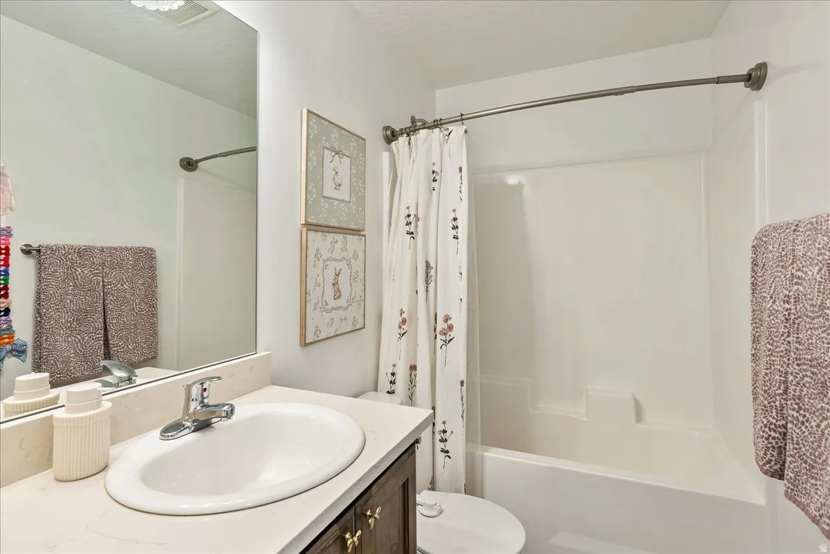 Bathroom featuring a single vanity with an integrated sink, polished chrome faucet, and wood-finish cabinetry