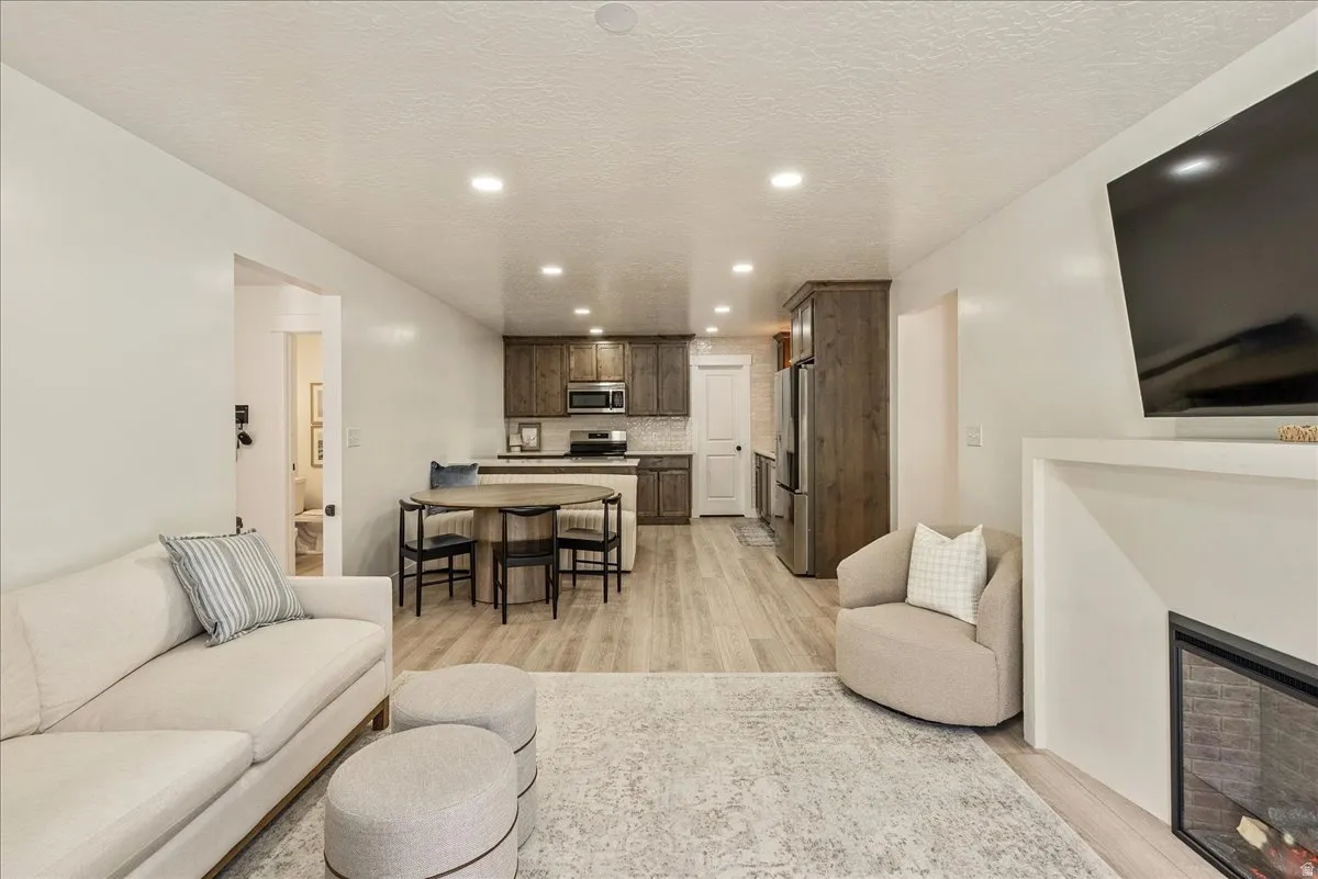 Open-concept living space featuring wood-finish flooring, recessed lighting, and a built-in fireplace