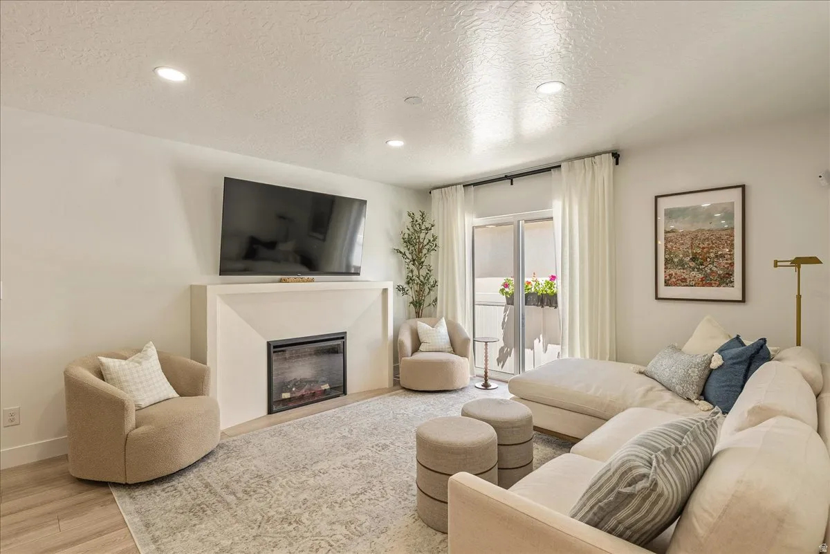 Living space featuring a built-in electric fireplace with mantle, recessed lighting, and wood-finish flooring