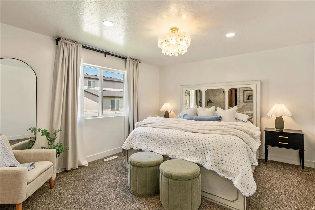Bright interior featuring a double window with light-filtering curtains, overhead decorative light fixture, recessed lighting, and textured carpeting