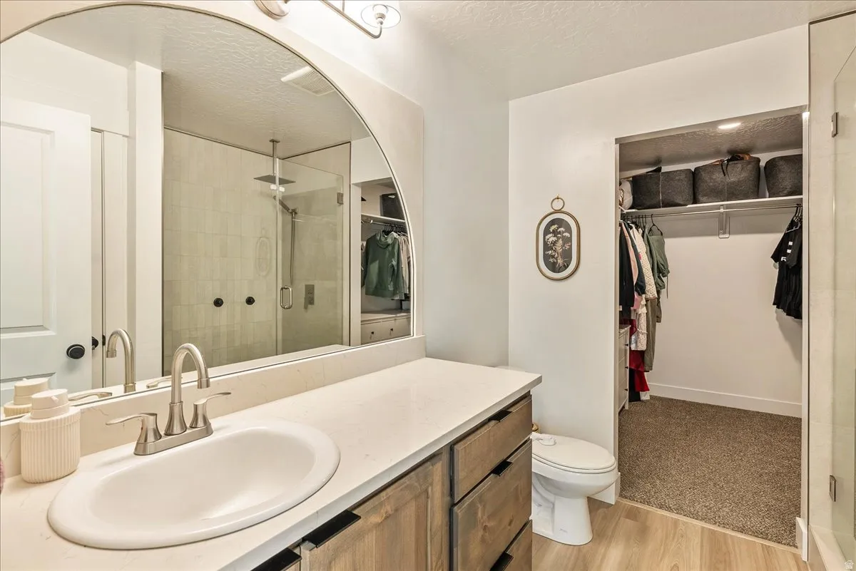 Bathroom featuring a wood-finish vanity with a single basin sink, light-toned countertop, and brushed nickel faucet
