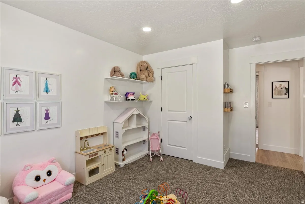 Recessed lighting illuminates the space, featuring neutral carpeting and white painted walls