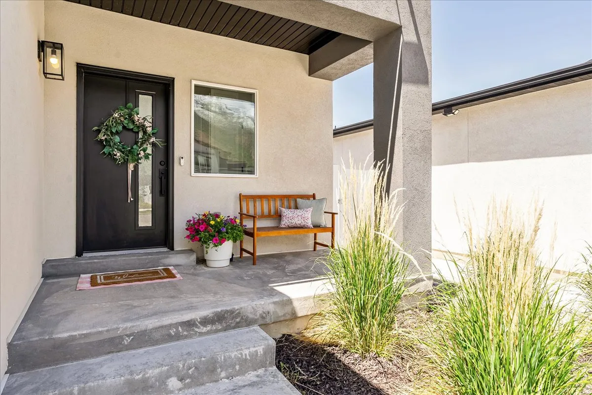 Contemporary exterior featuring a solid black front door with a vertical glass insert, a complementary side window, and an overhead exterior light fixture
