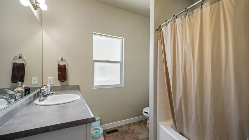 Main Upstairs Bathroom featuring a white vanity with an integrated sink, a large wall-mounted mirror, and a frosted window