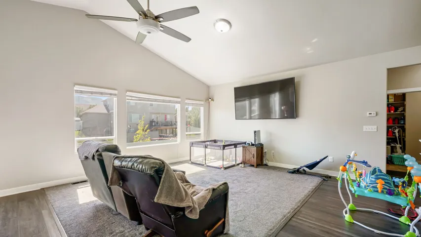 Living room featuring vaulted ceilings, multiple windows for great lighting, new carpet,  LVP flooring, a ceiling fan, and a mounted light fixture