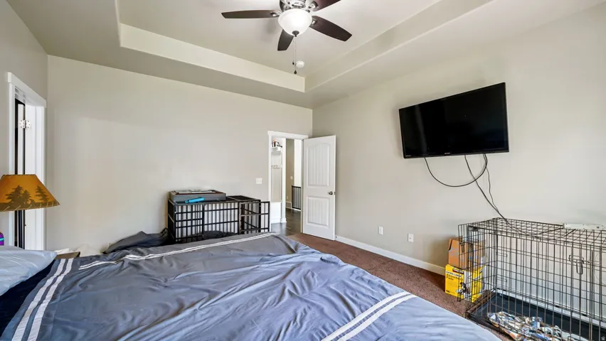 Primary Bedroom, Spacious room featuring a tray ceiling with a ceiling fan, neutral wall paint, and brown carpeting