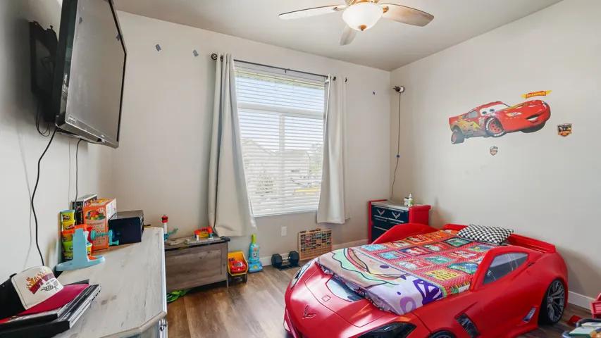 Upstairs Bedroom featuring LVP flooring, a ceiling fan with integrated lighting, and a window with blinds and drapes