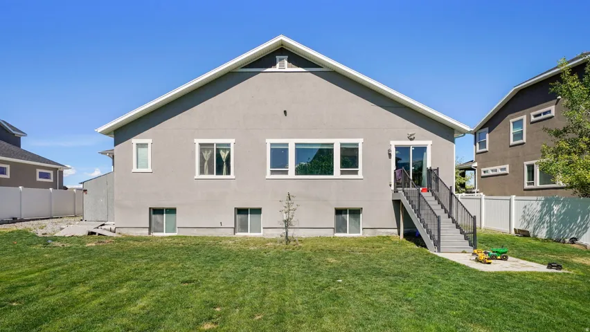 Exterior featuring a stucco finish, multiple windows, and a sliding glass door leading to a deck with stairs to the yard
