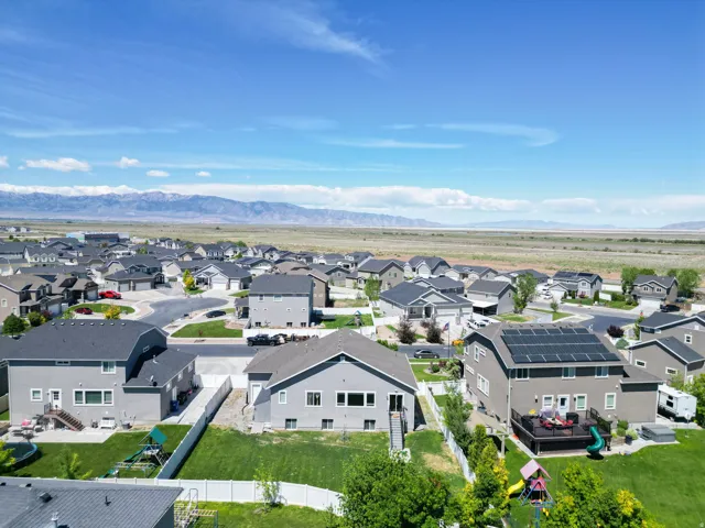 Residential neighborhood with mountain backdrop, featuring a cul-de-sac and multiple properties with solar panel installations