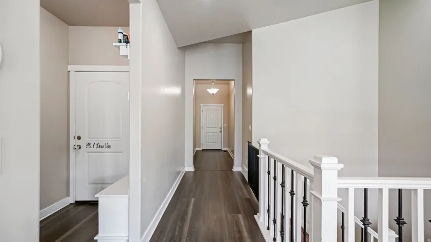 Entryway featuring wood-finish flooring, light neutral wall tones, white trim, and a white staircase with black wrought iron balusters