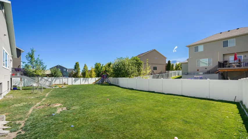 Expansive grassy yard enclosed by a white privacy fence