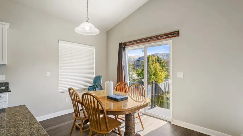 Dining area featuring a vaulted ceiling, LVP flooring, and a sliding glass door providing outdoor access