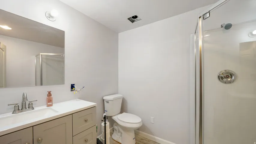 Bathroom featuring a single vanity with a white countertop, chrome faucet, and a large wall-mounted mirror