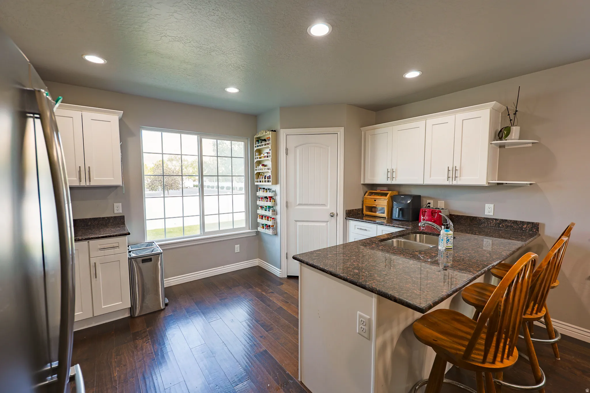 Kitchen with bar, granite counter tops, canned lighting and natural light.