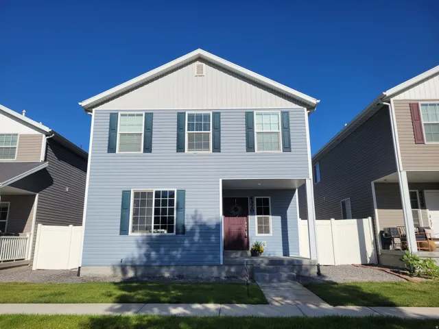 Two-story residence featuring light blue siding with white trim and dark blue shutters