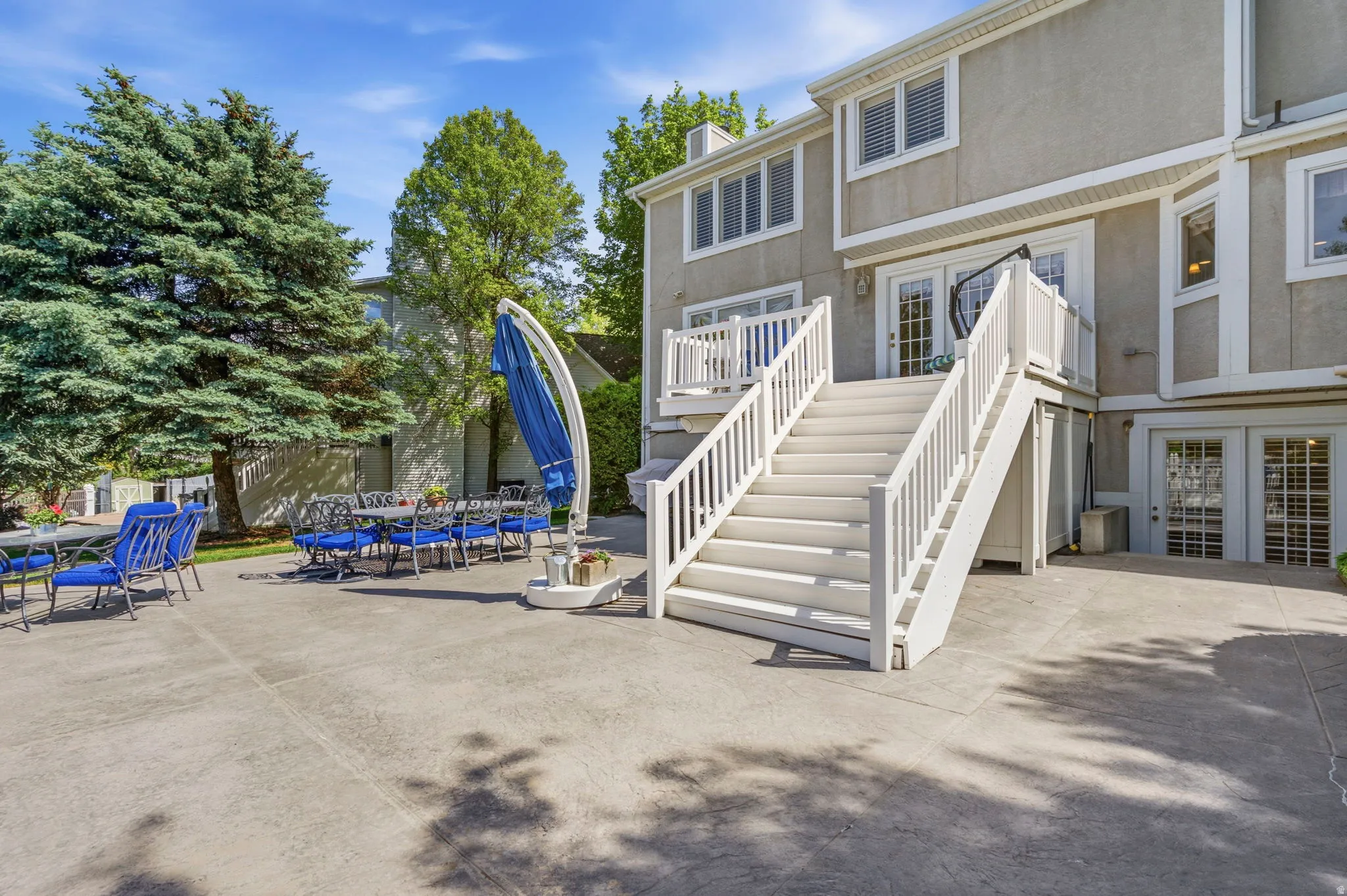 Expansive concrete patio area with a white wood deck and staircase