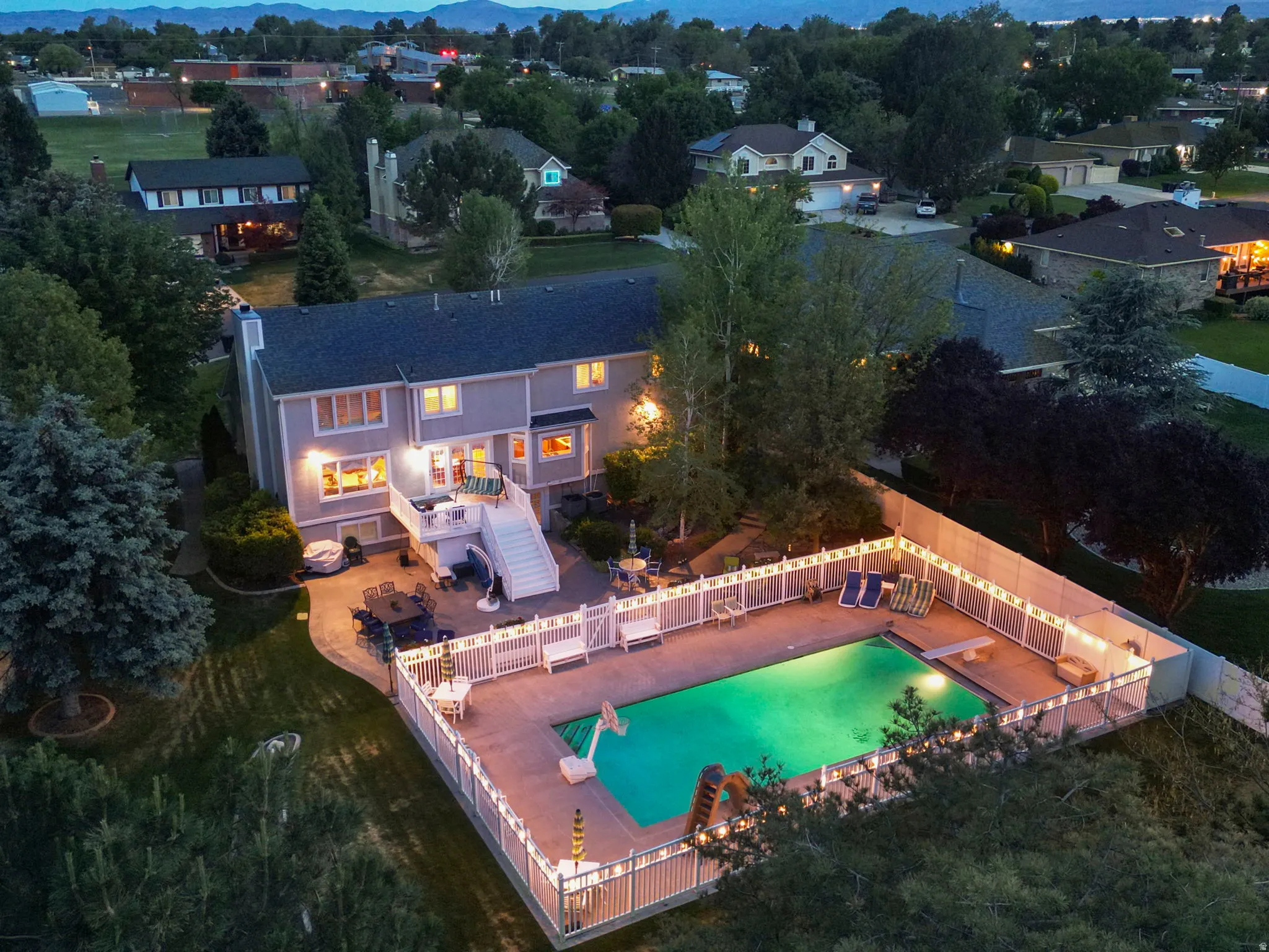 Rear exterior featuring a multi-level deck, a fenced swimming pool, and a paved patio area