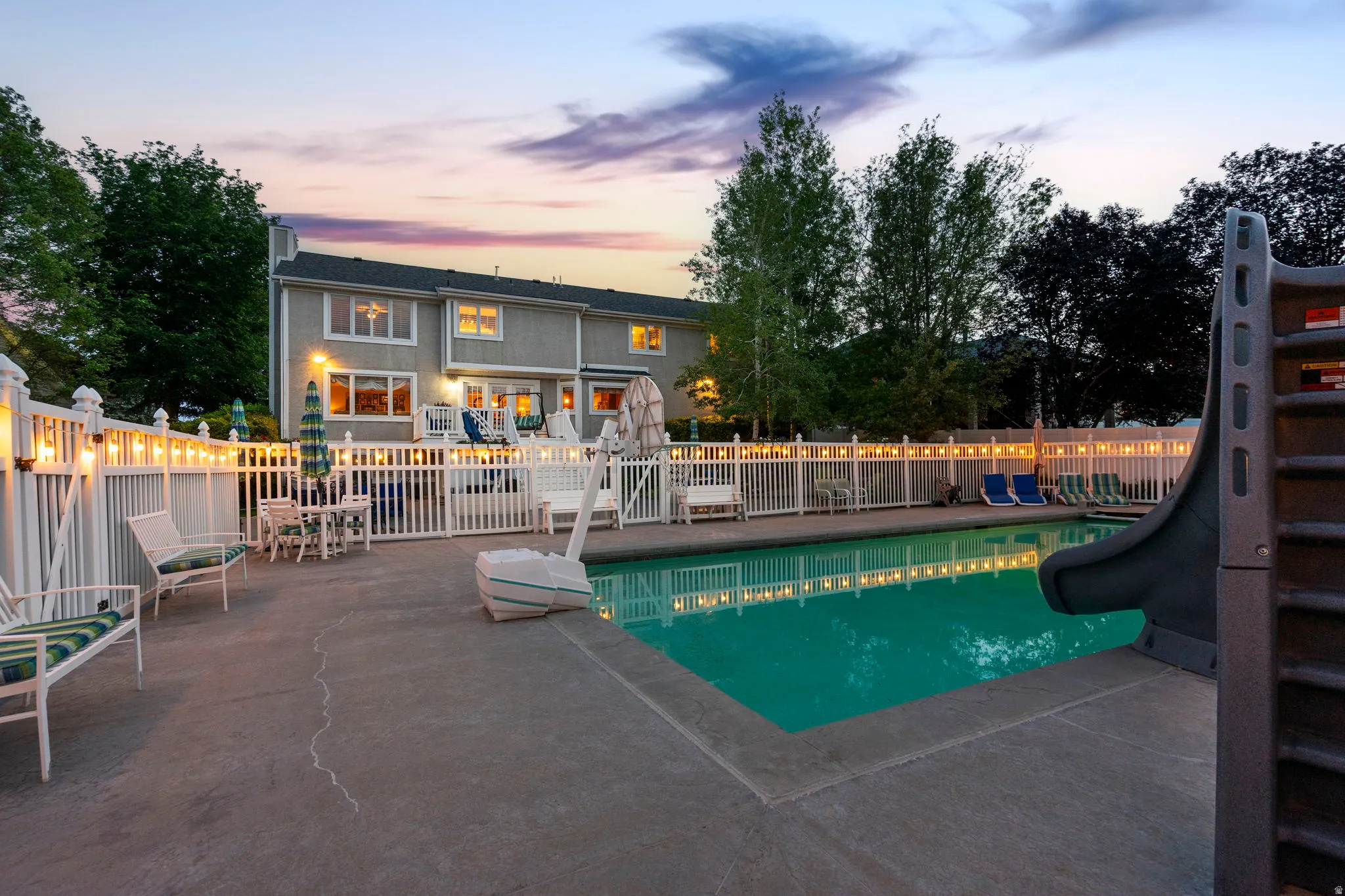 In-ground swimming pool with a concrete surround and integrated slide