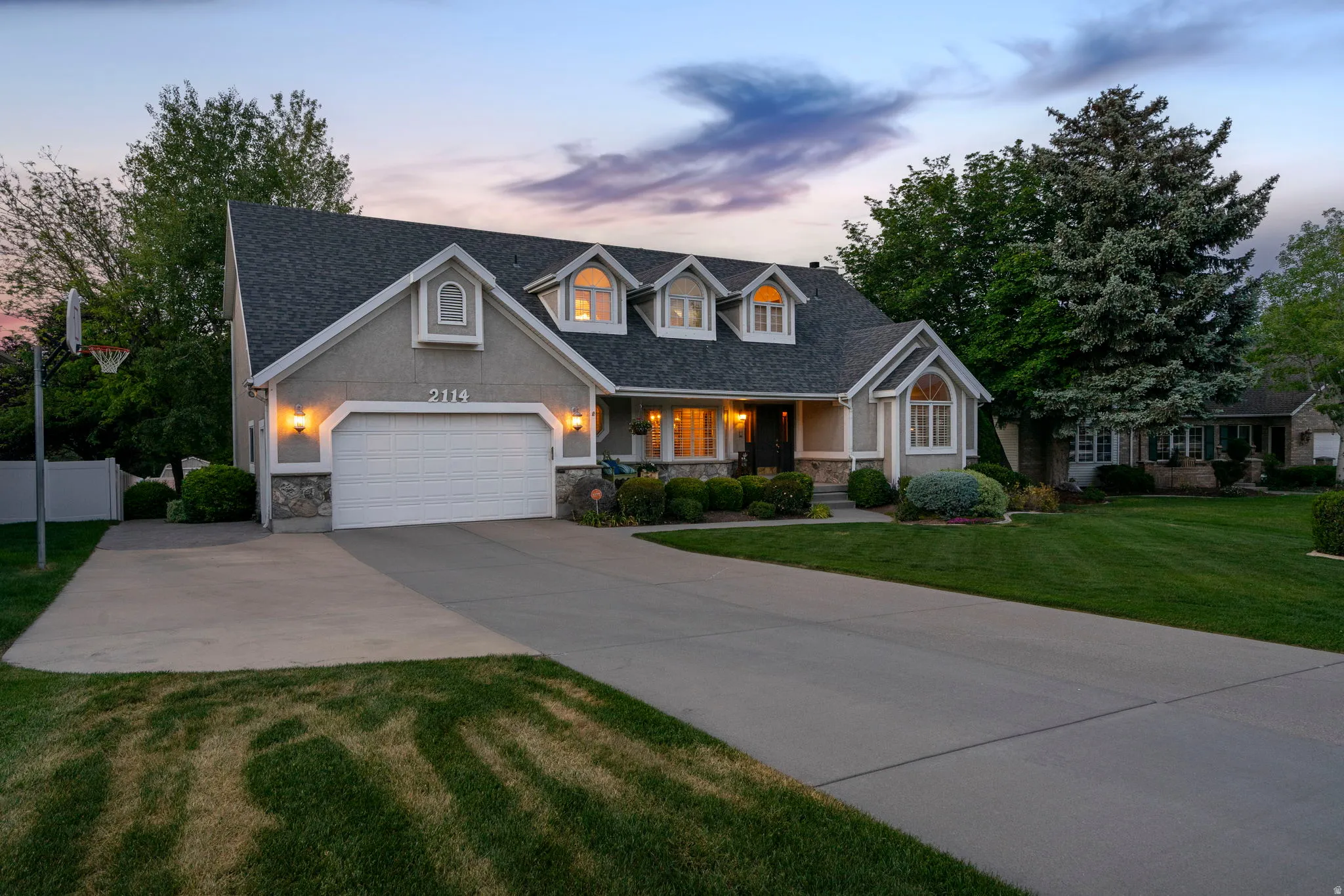 Traditional-style residence featuring a two-car garage, stone accents, and dormer windows