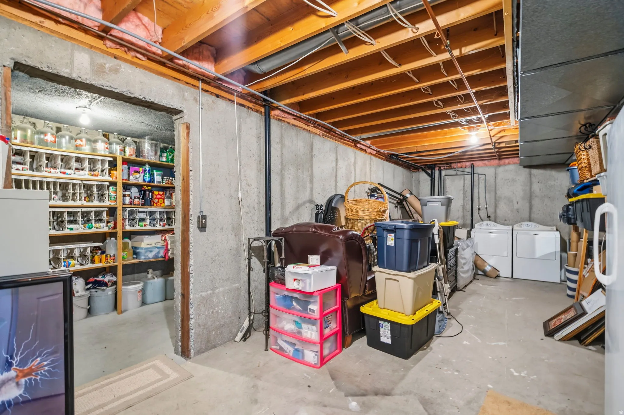 Unfinished basement featuring exposed wood joists, concrete block walls, and concrete flooring