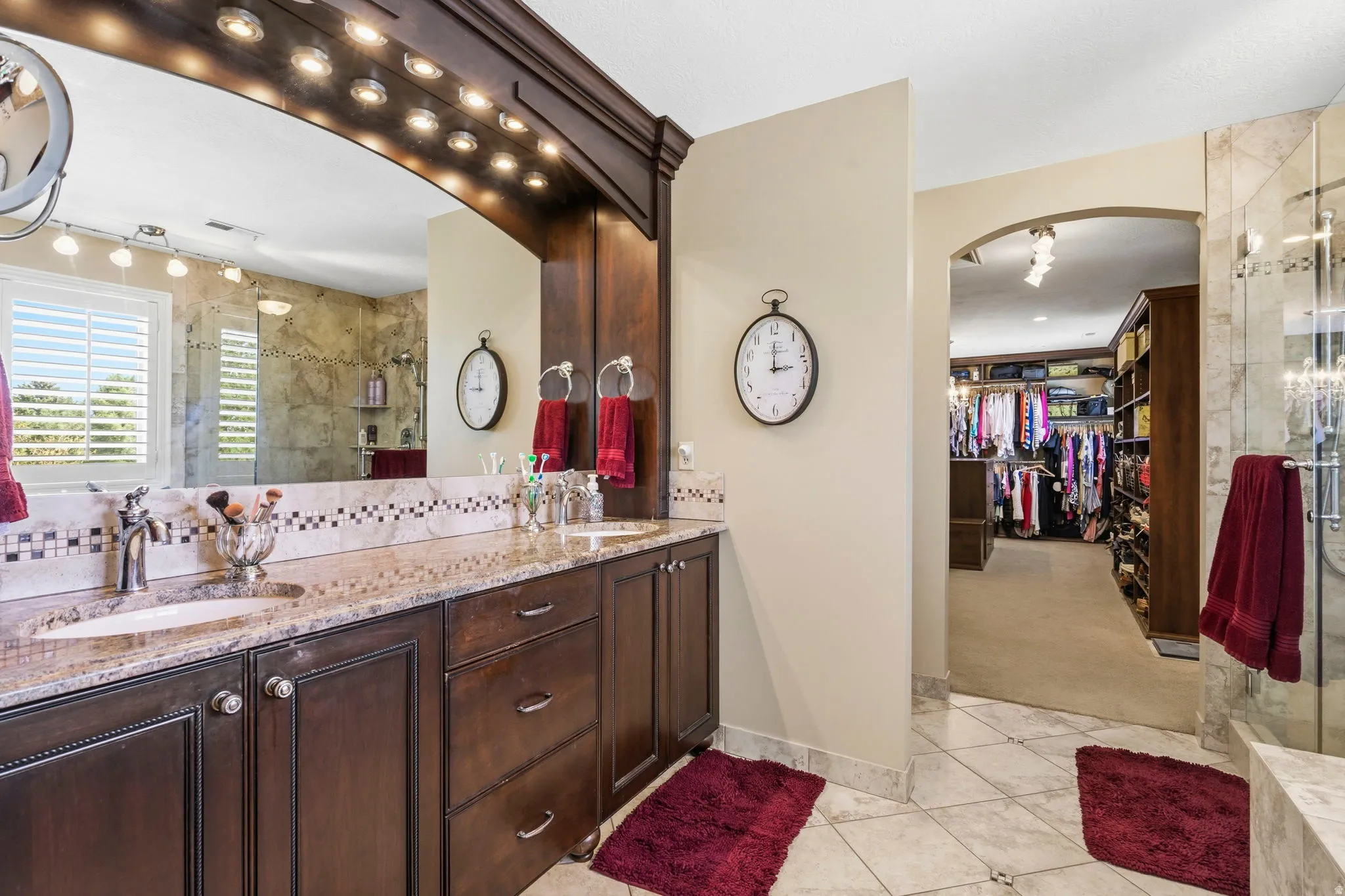 Dual vanity featuring dark wood cabinetry, light speckled countertops, and a tiled backsplash