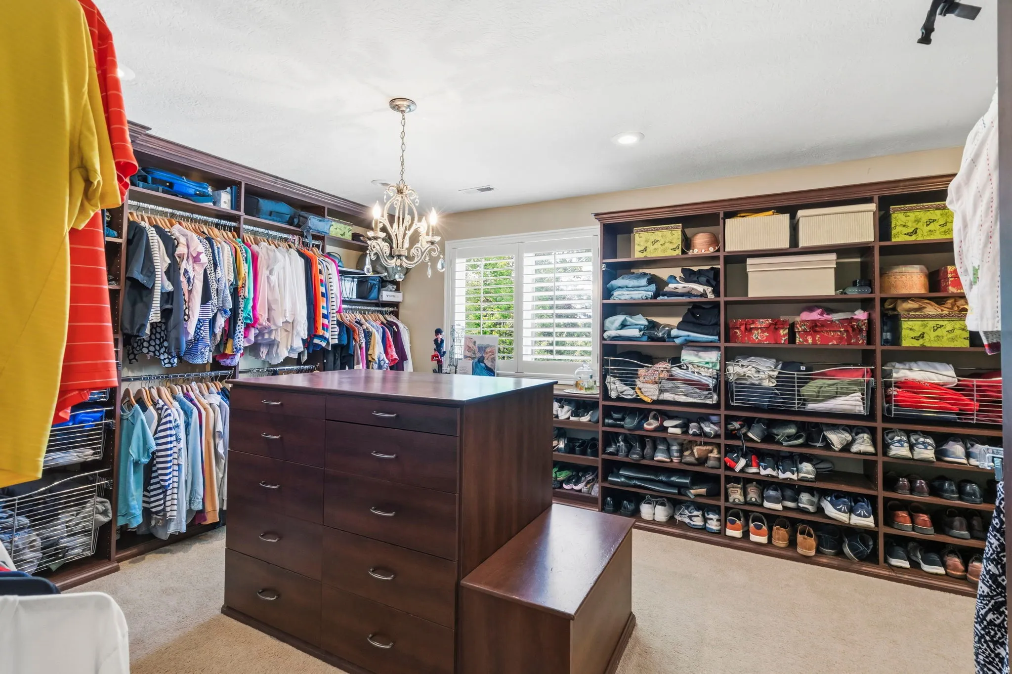 Spacious custom-built closet featuring extensive dark wood-finish shelving and hanging storage
