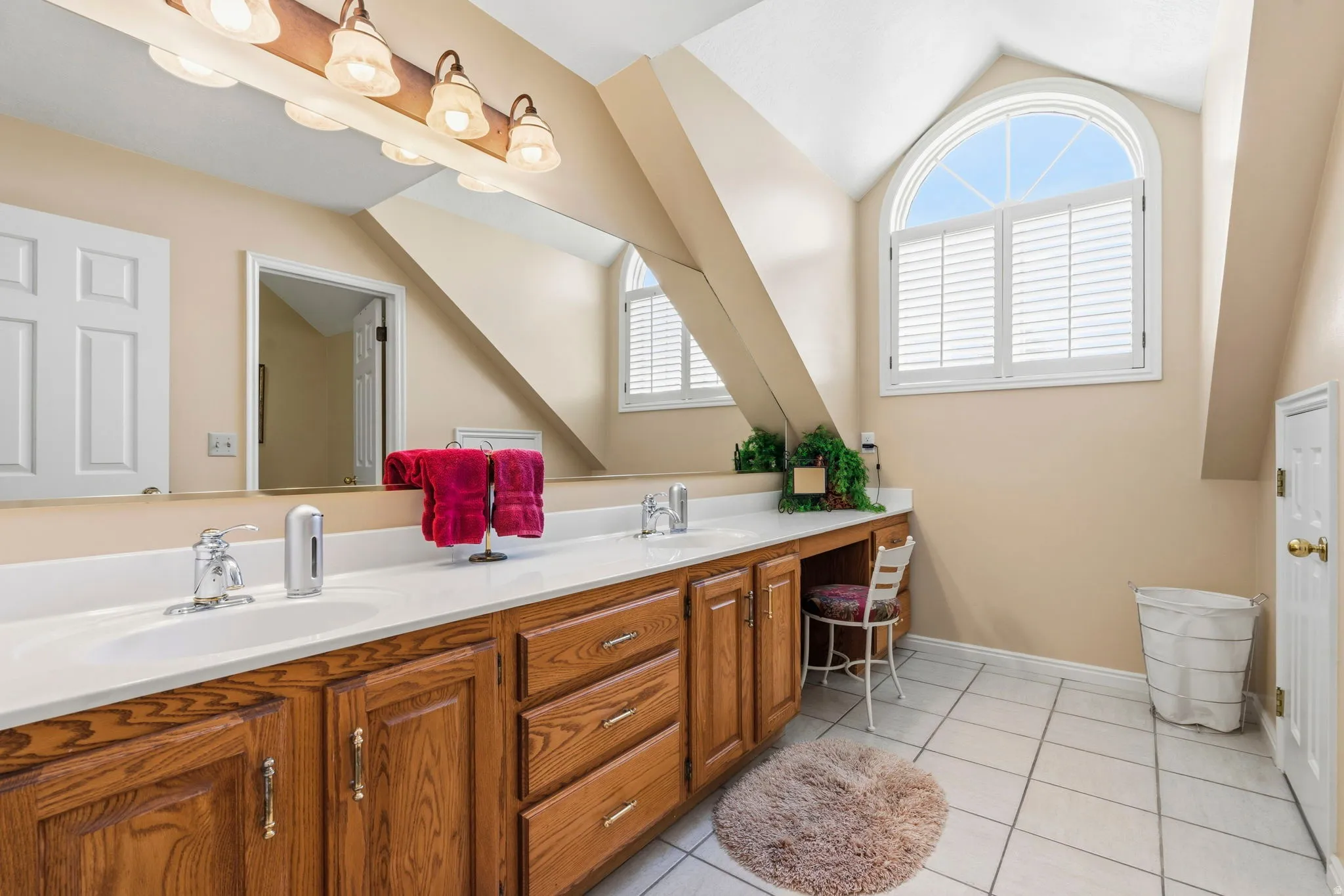Bathroom with a double vanity featuring wood cabinetry, white countertops, and chrome fixtures
