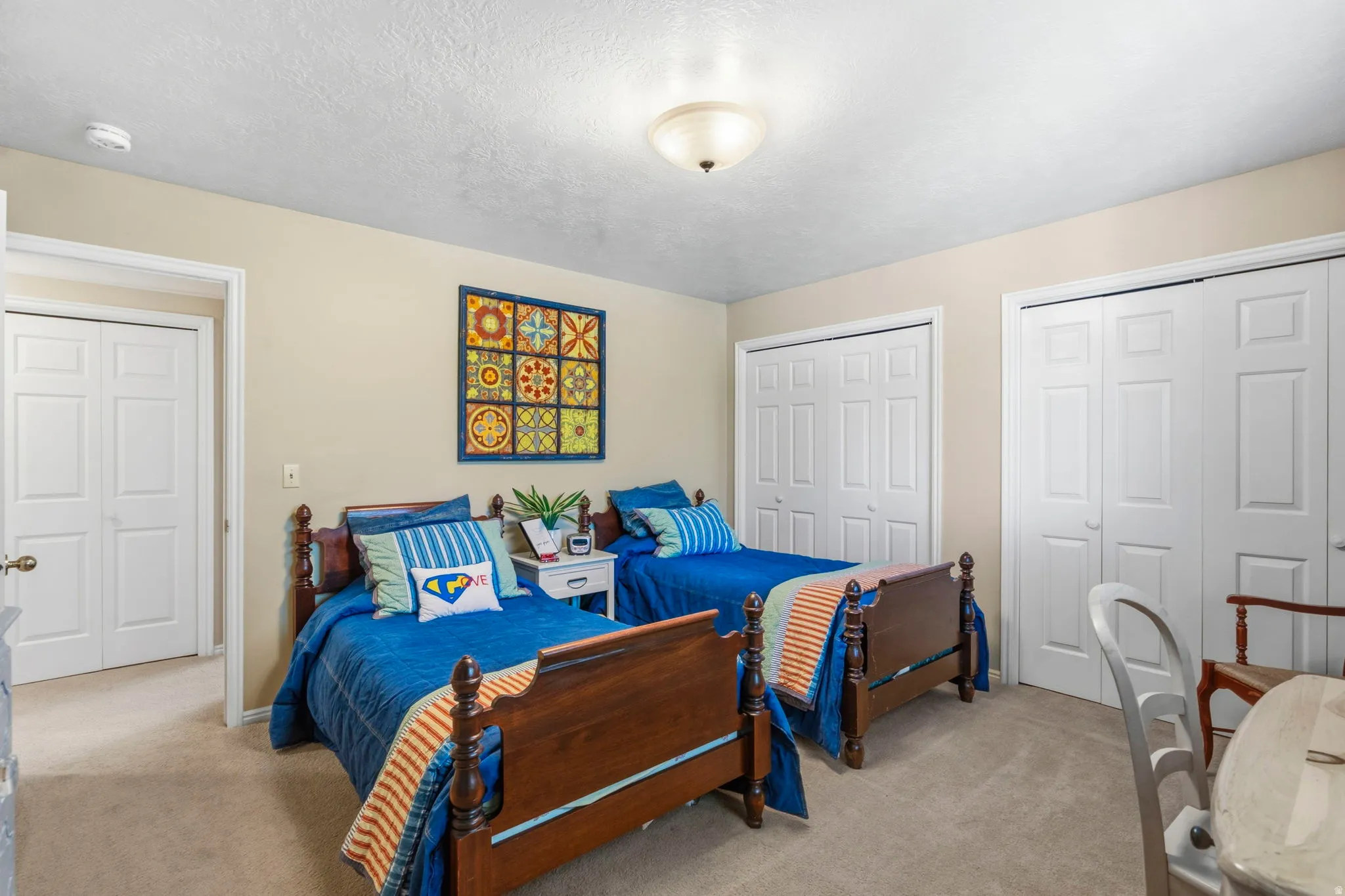 Carpeted room with a ceiling-mounted light fixture, two white bi-fold closets, and an additional white bi-fold door