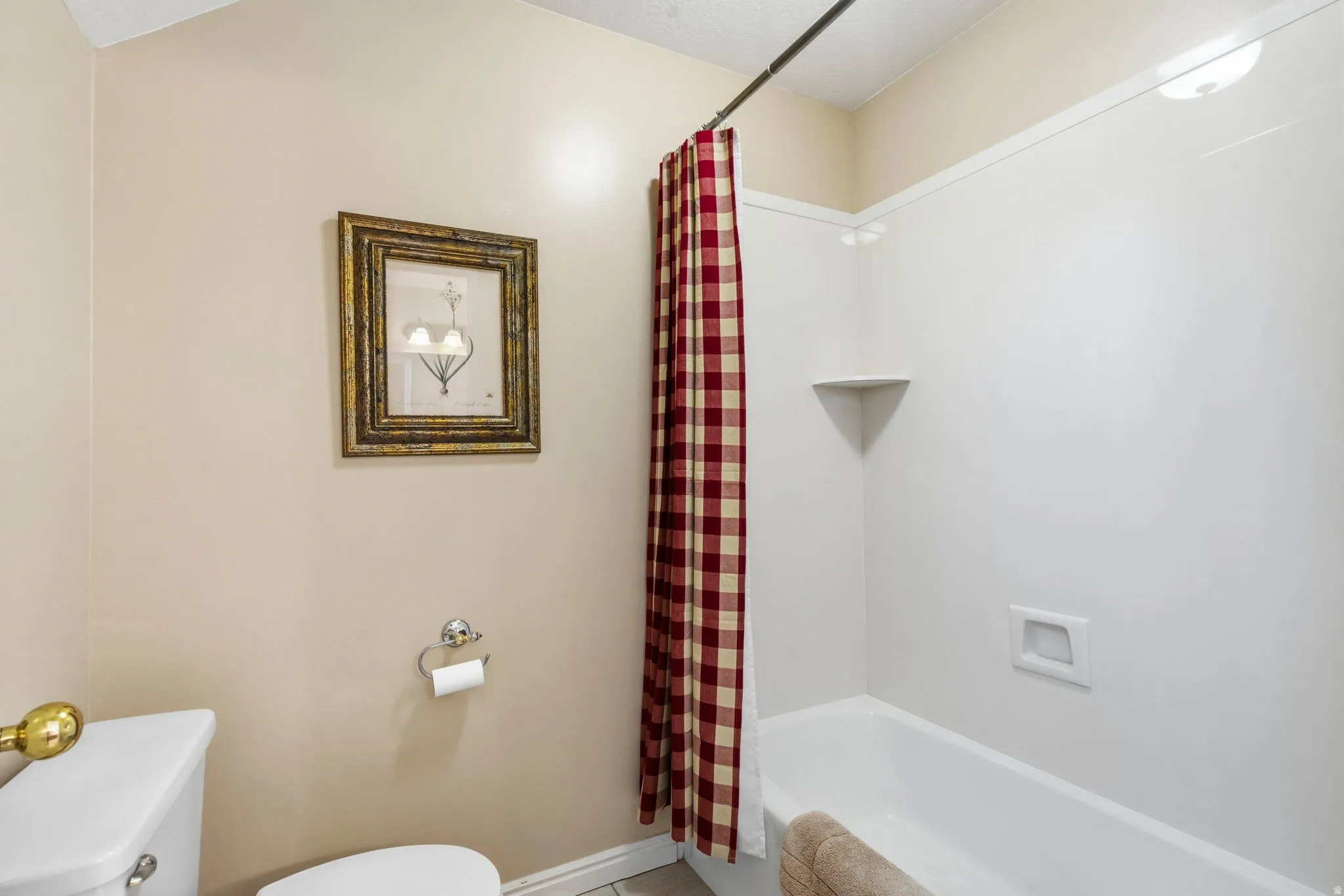 Bathroom featuring a white bathtub and shower surround, a built-in corner shelf, and a ceiling light fixture