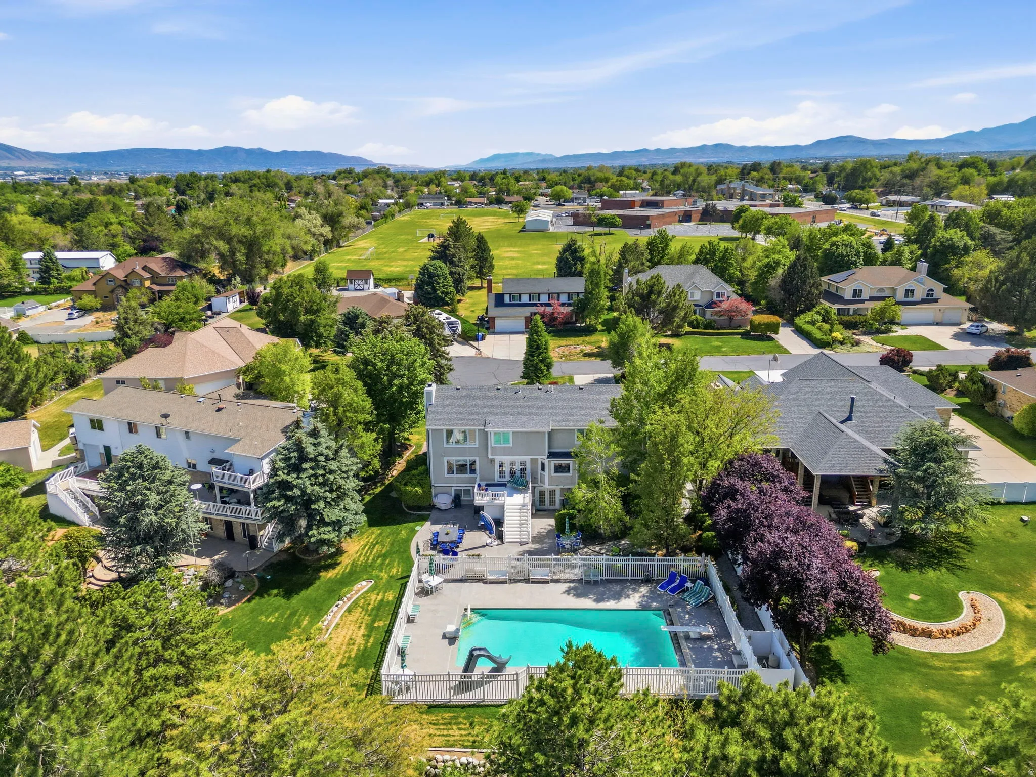 Expansive property featuring a fenced swimming pool, spacious patio area, and mature landscaping