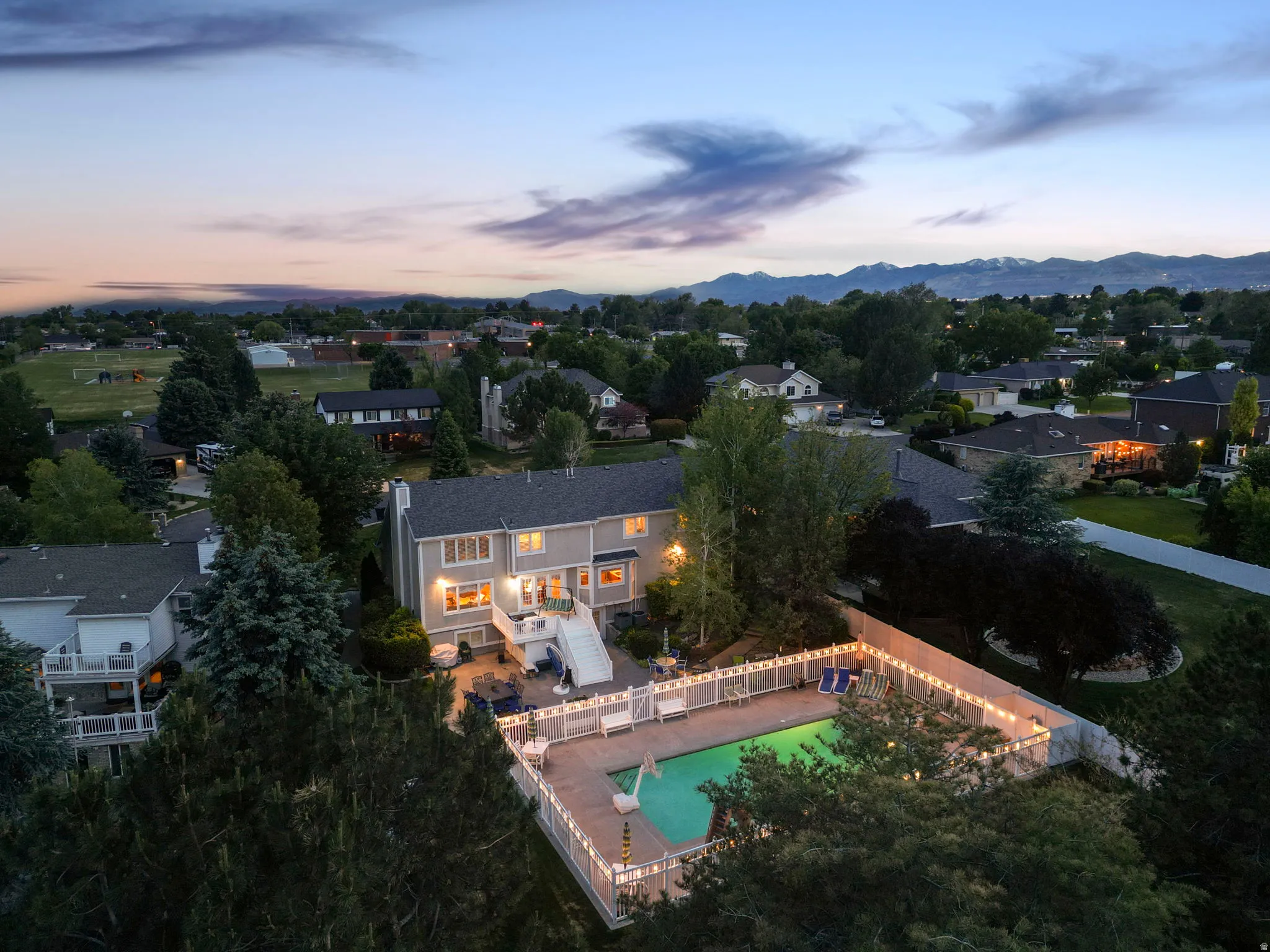 Rear exterior featuring a multi-level deck, a fenced swimming pool with surrounding patio, and a backdrop of distant mountains