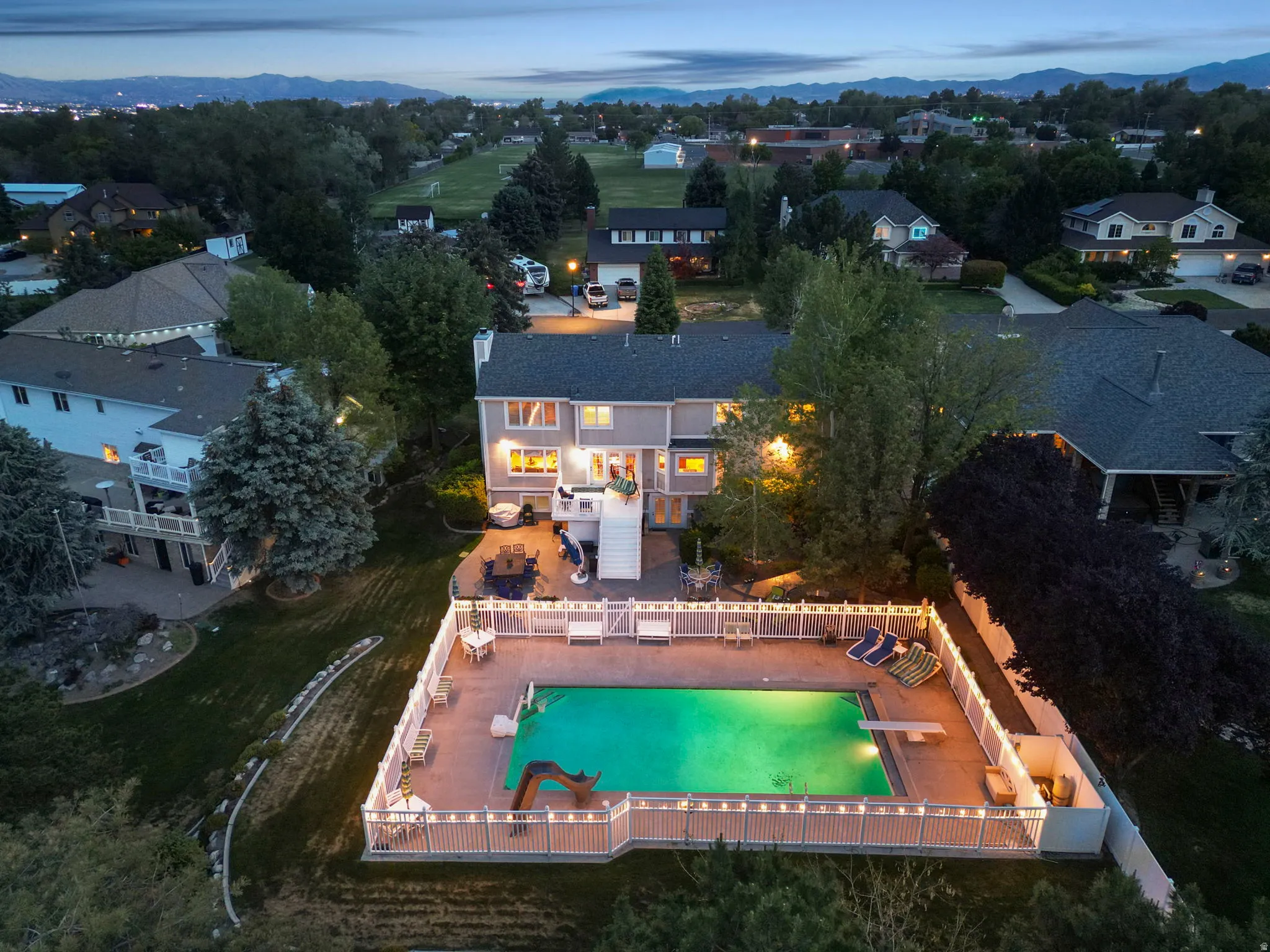 Backyard featuring a fenced in-ground swimming pool, surrounding patio, and a diving board
