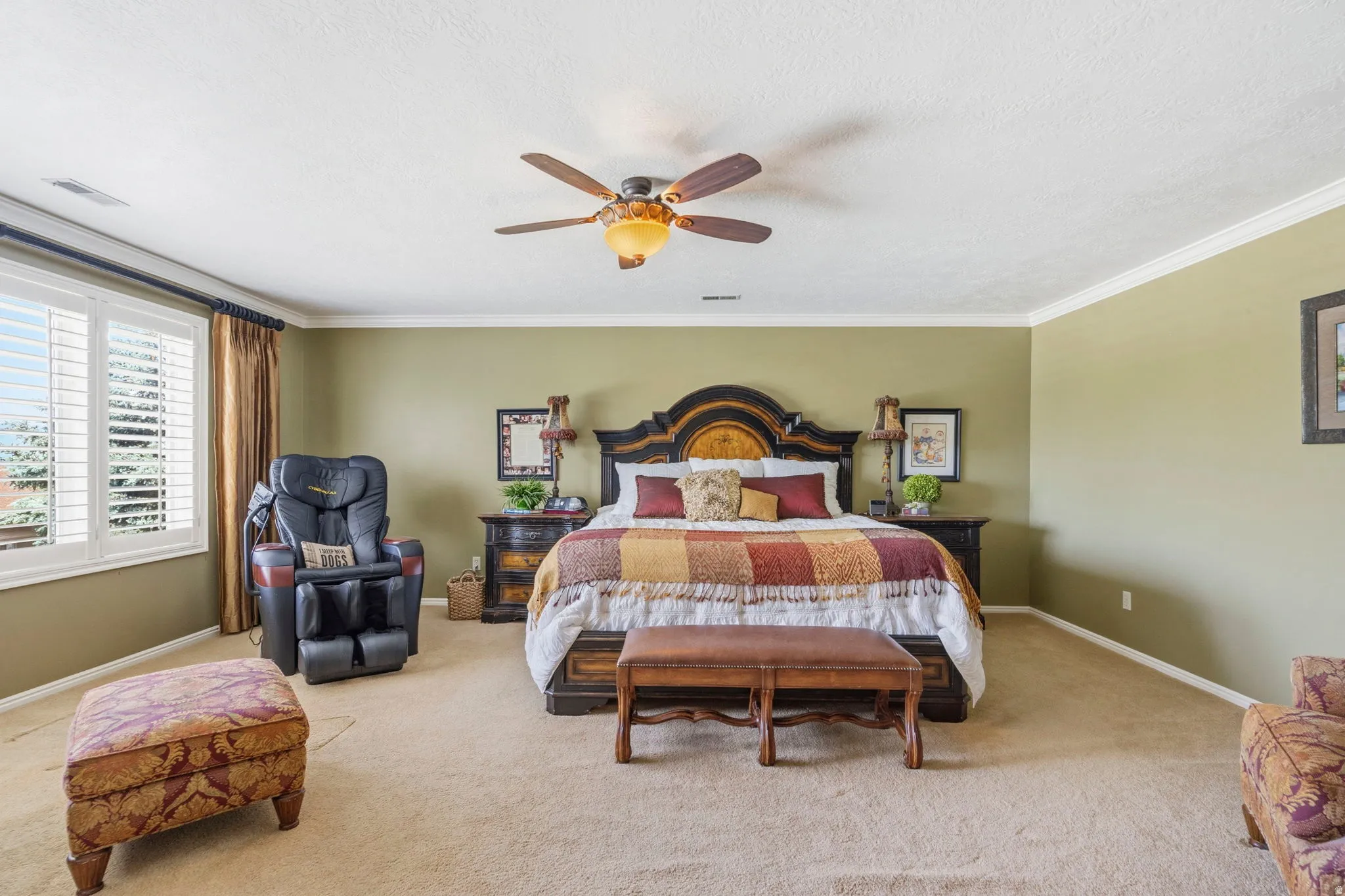 Spacious bedroom featuring neutral carpeting, light olive wall tones, and white crown molding