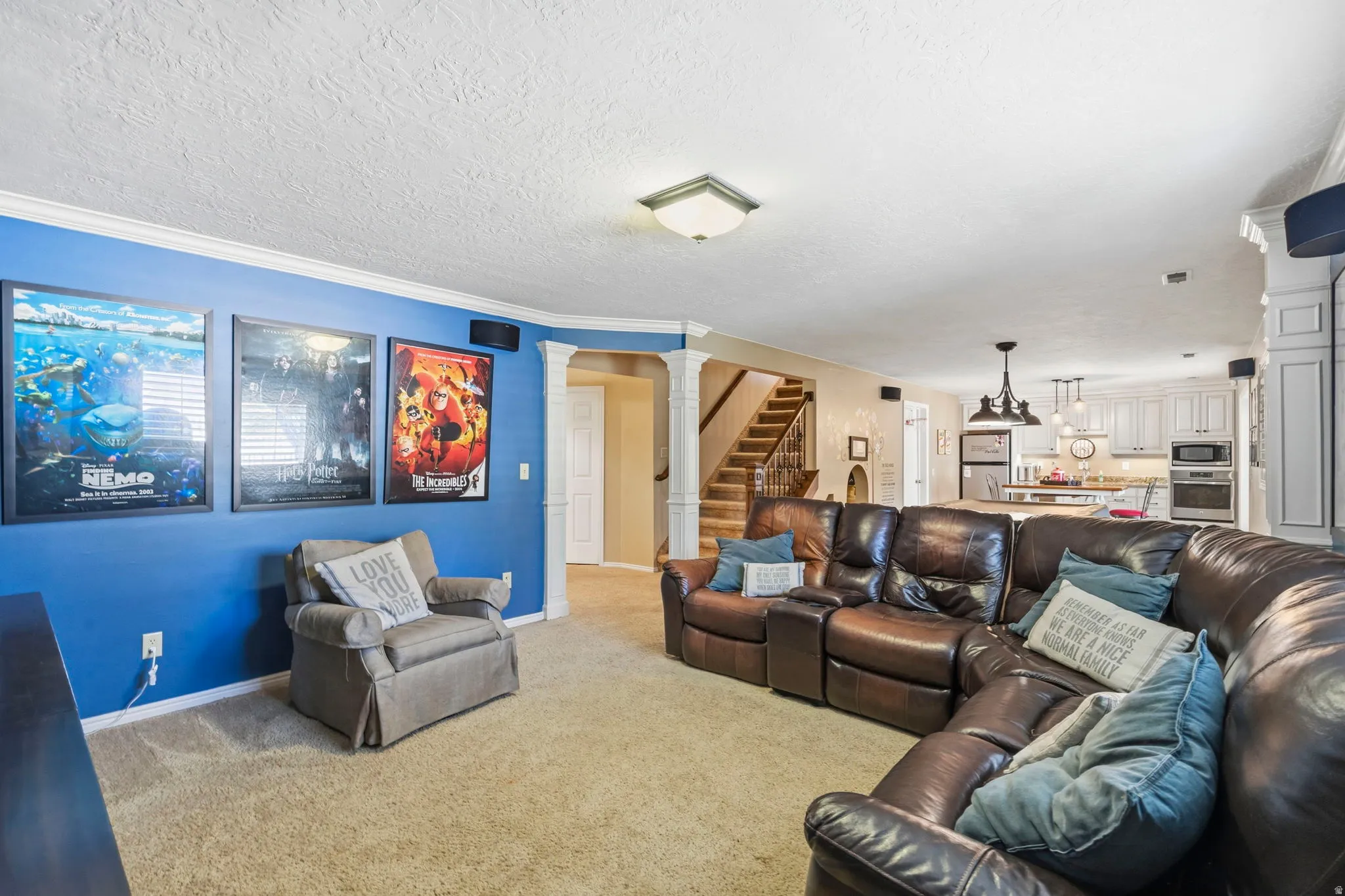 Open-concept living space featuring a carpeted floor, white crown molding, and a blue accent wall
