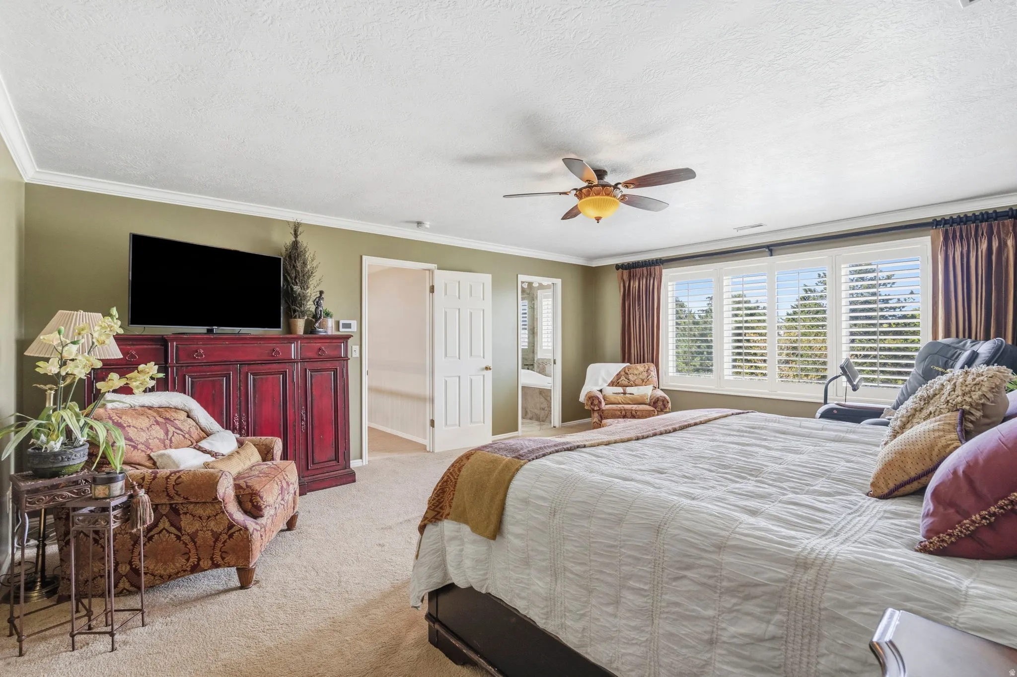 Spacious room featuring carpeting, crown molding, a ceiling fan, and multiple windows with plantation shutters