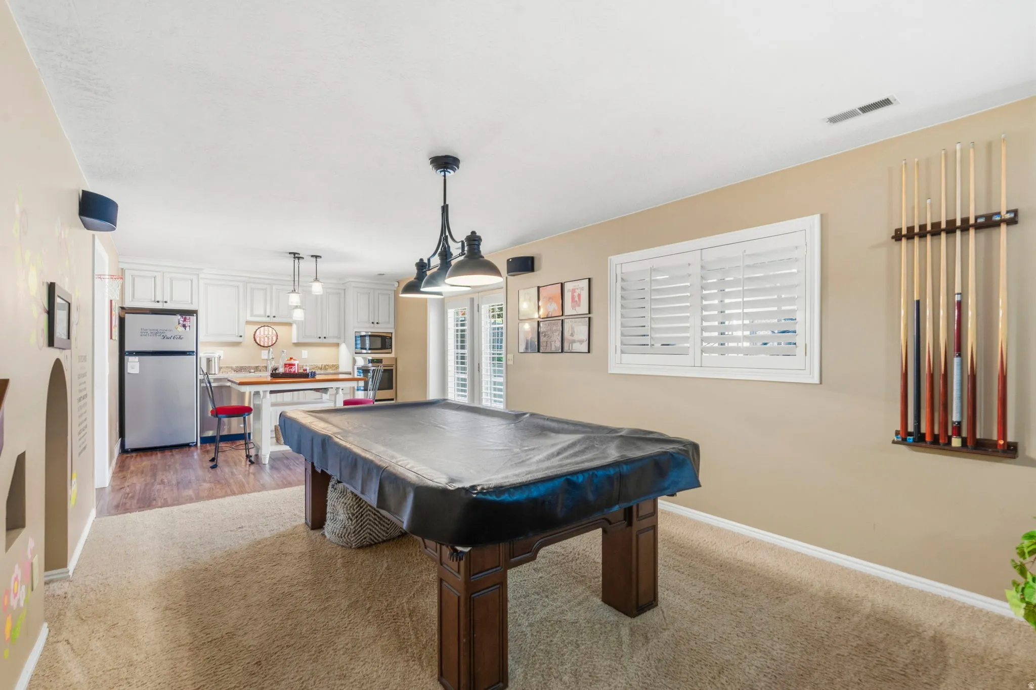 Entertainment room featuring a billiards table with an overhead multi-bulb light fixture, a built-in cue rack, and carpeted flooring