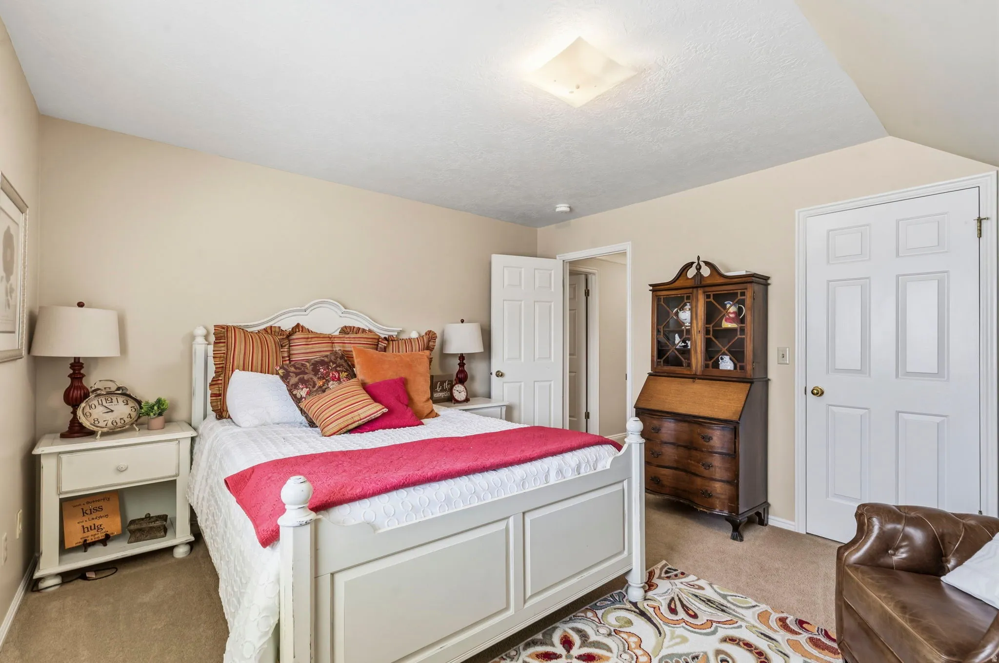 Carpeted bedroom featuring a white paneled bed frame, white paneled doors, and a ceiling-mounted light fixture
