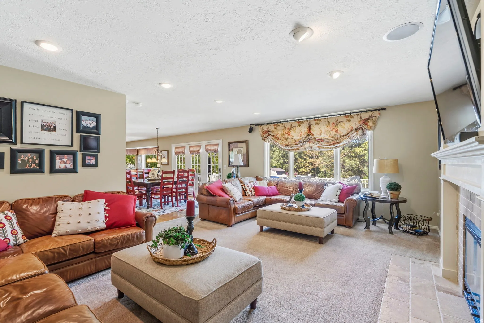 Spacious living area featuring recessed lighting, a large window with patterned valance, and a tiled fireplace
