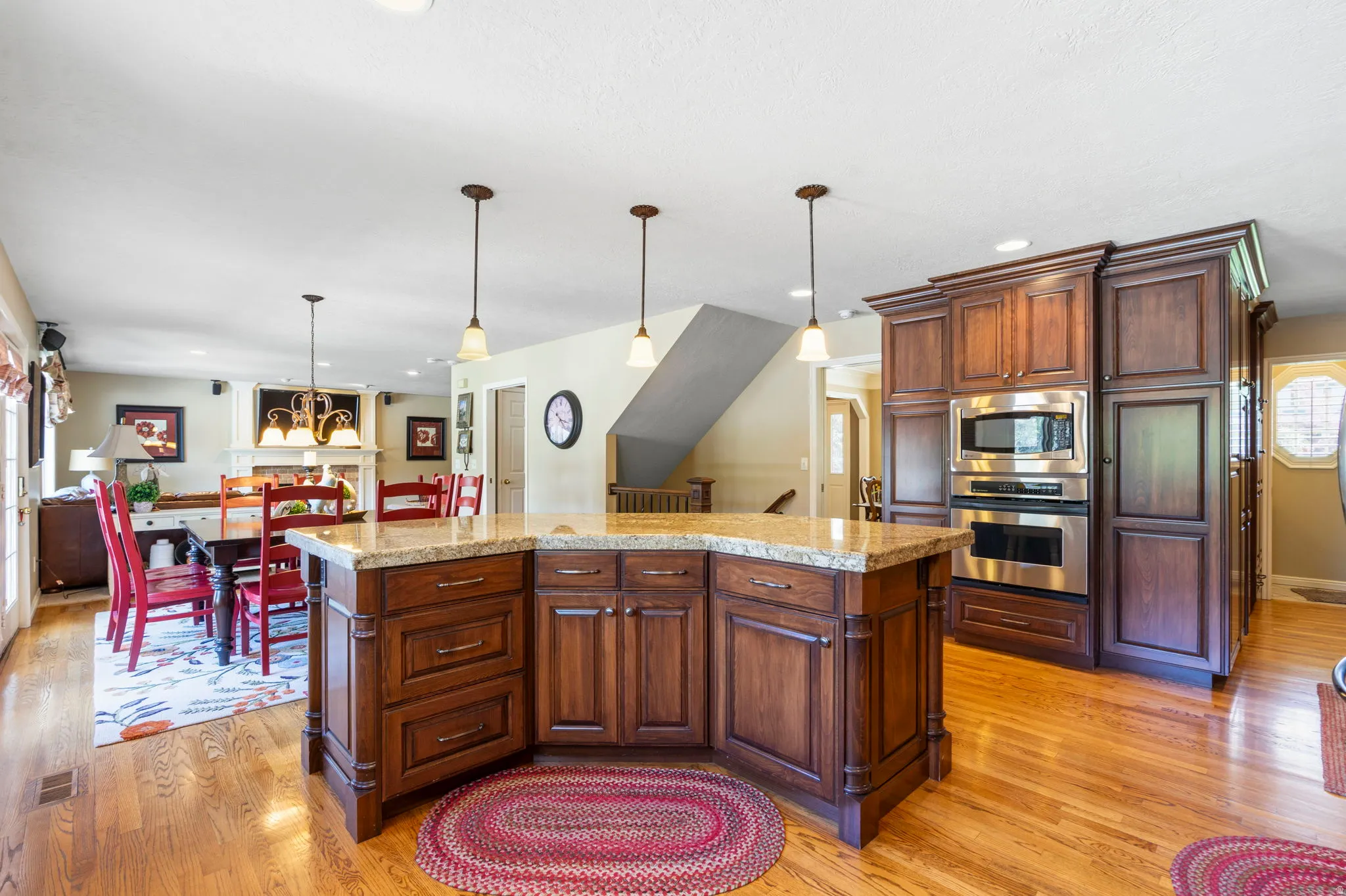 Kitchen island with a light-toned countertop, wood-finish cabinetry, and three pendant lights