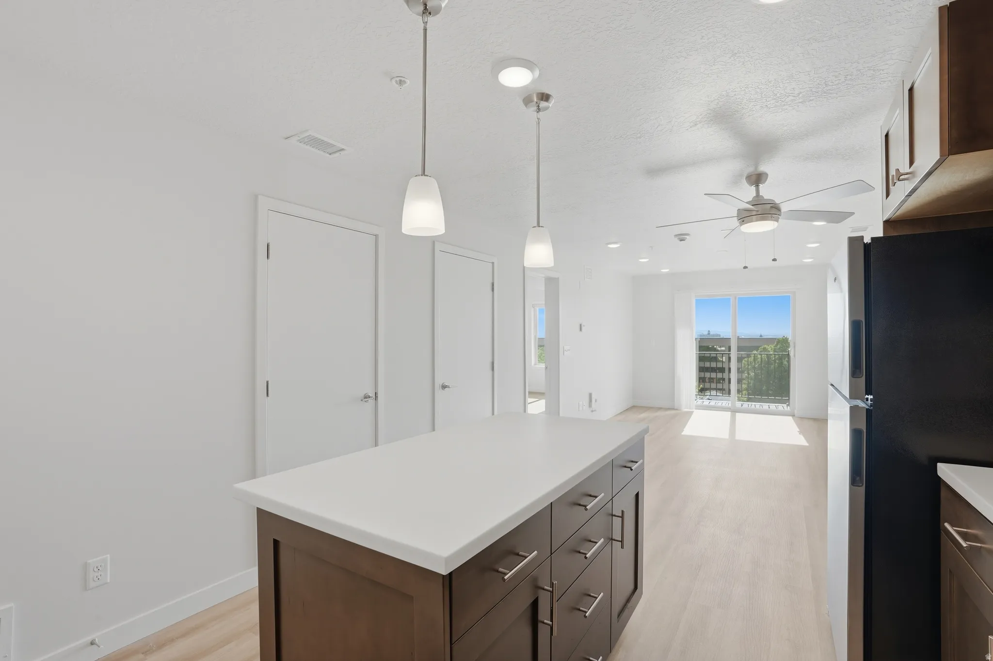 Open-concept kitchen and living area featuring a central island with white quartz countertops, beautiful cabinetry, and stainless steel appliances